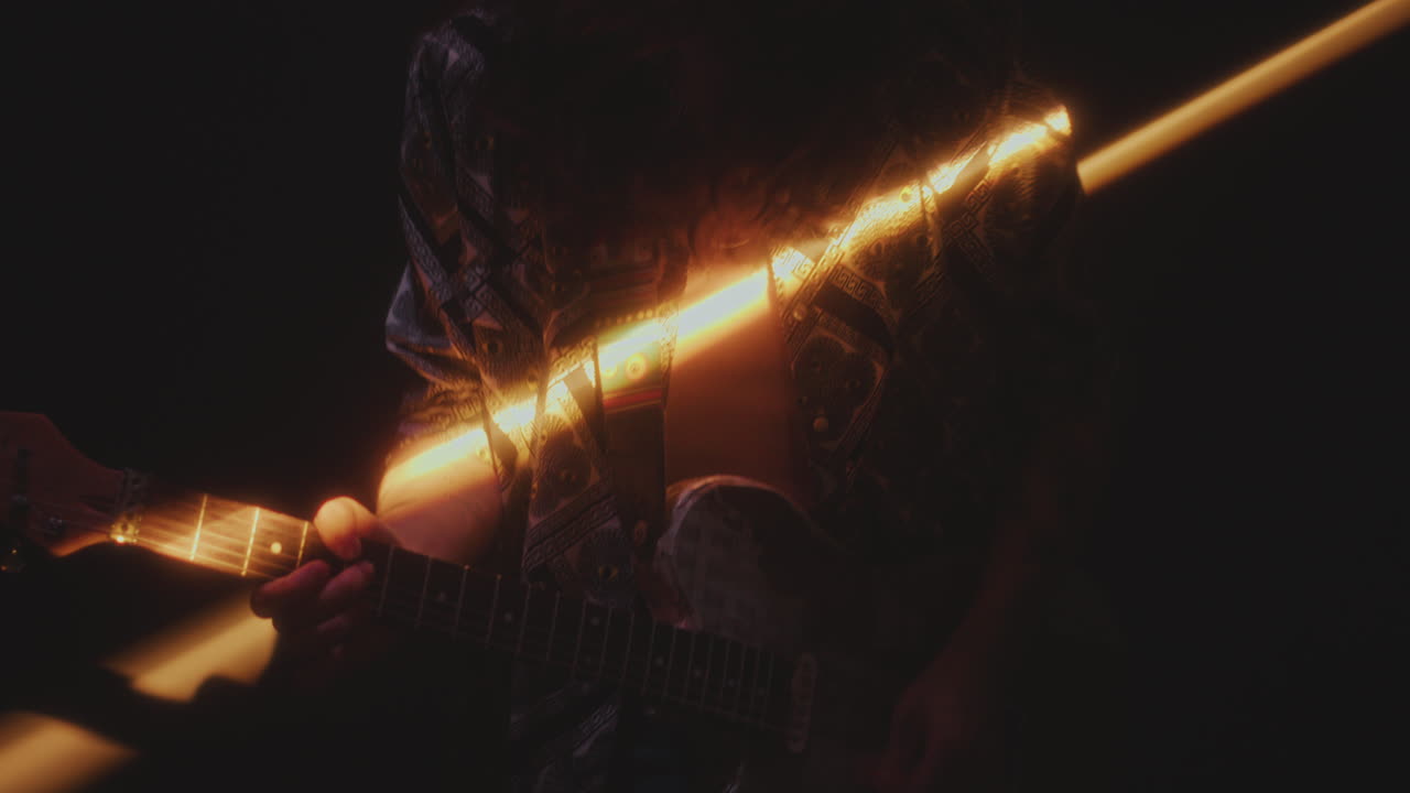Rock Musician Playing Guitar in Dark Studio with Light Beam