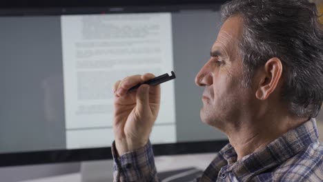 Man-reading-written-document-on-computer-is-thoughtful.