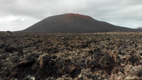 volando bajo y rápido hacia una colina sobre rocas volcánicas