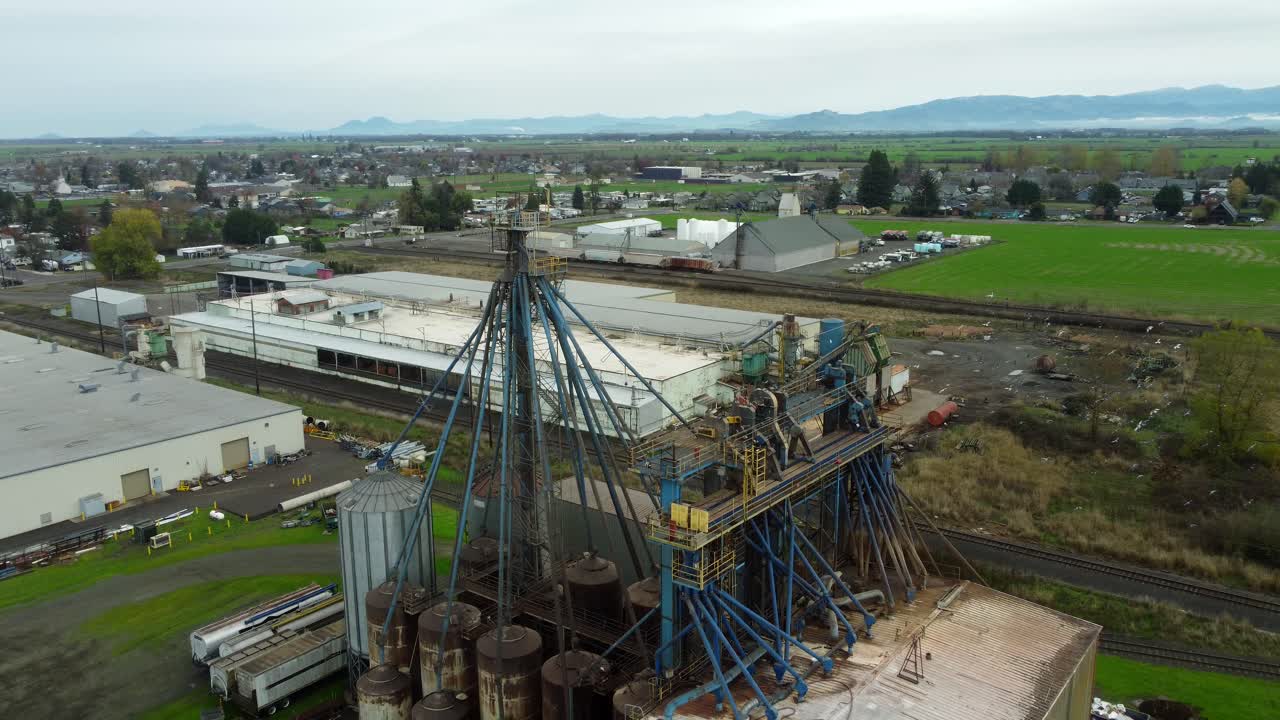 USA, OR, Harrisburg, , 2025-11-23 - Vista con drone di uccelli che volteggiano attorno a un impianto di lavorazione chimica con vecchie tubature sporche che portano a una torre presso CHS Nutrition, in autunno.