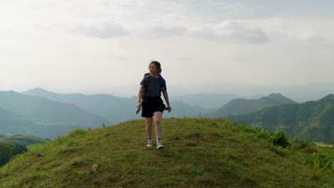 young asiatic female solo traveller walking in slow motion hiking mountains peak in remote natural travel destination