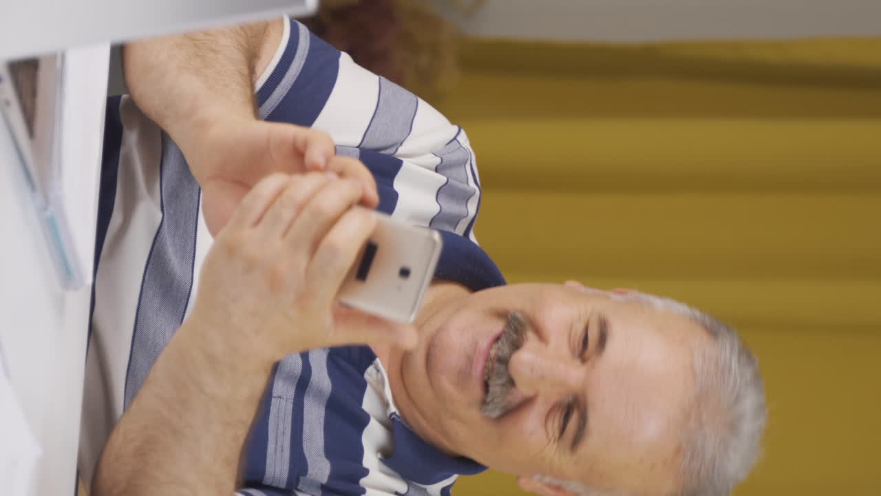 프리랜서 노인이 집에서 재미있고 행복하게 춤을 추는 수직 비디오.