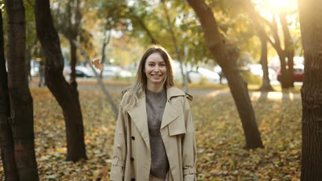 Glückliche-Frau-Wirft-Blätter-Im-Herbst-In-Zeitlupe-Und-Lächelt