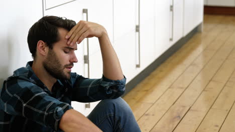 El-Hombre-Está-Sentado-Contra-Una-Pared-Con-Una-Expresión-Triste-En-Su-Rostro.