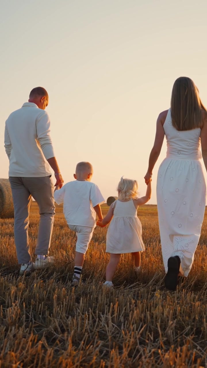 Famiglia che cammina insieme attraverso un campo di grano dorato al tramonto
