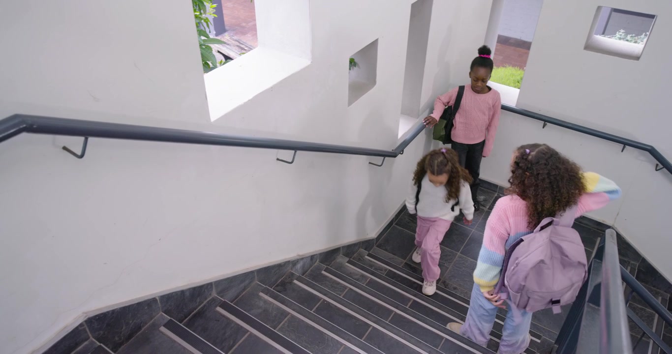 Afroamerikanske teenagepiger går op ad skoletrappen, justerer rygsække på vej til undervisning, plads til tekst