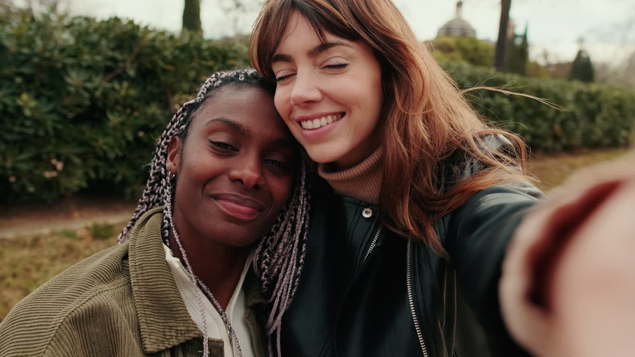 Two Happy Multi-Ethnic Women Taking a Selfie in a Park