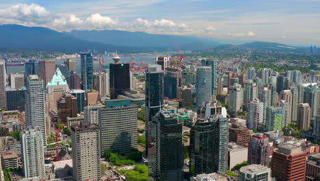 Construction-Sites-And-City-Skyline-In-Downtown-Vancouver-With-Distant-View-Of-Harbour-Centre-Lookout-And-Vancouver-Harbour-At-Daytime