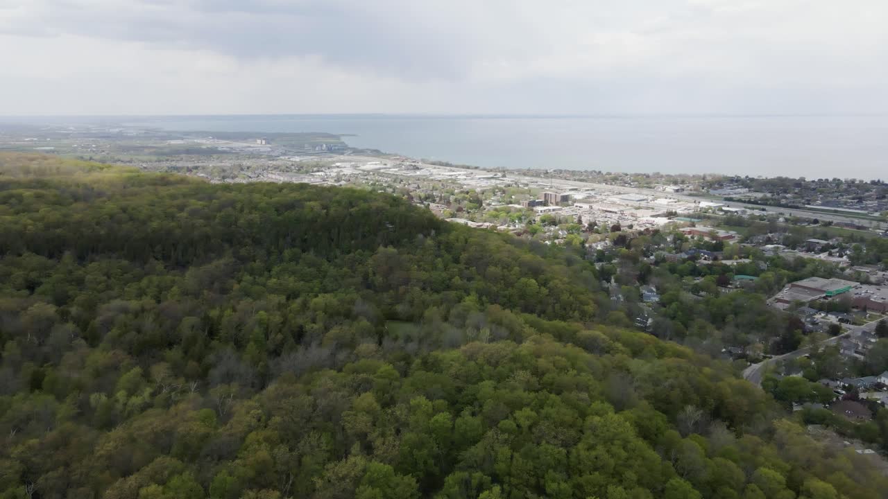 Aerial flyover green forest and coast city named Grimsby and Lake Ontario in backgrounds