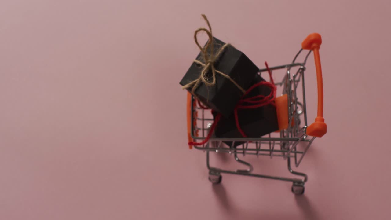 video de un carrito de compras con cajas y espacio de copia en fondo rosa