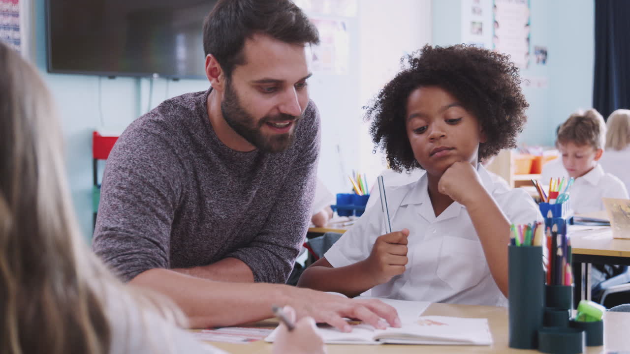 maestra de escuela primaria dando apoyo a una alumna que lleva uniforme uno a uno en el aula