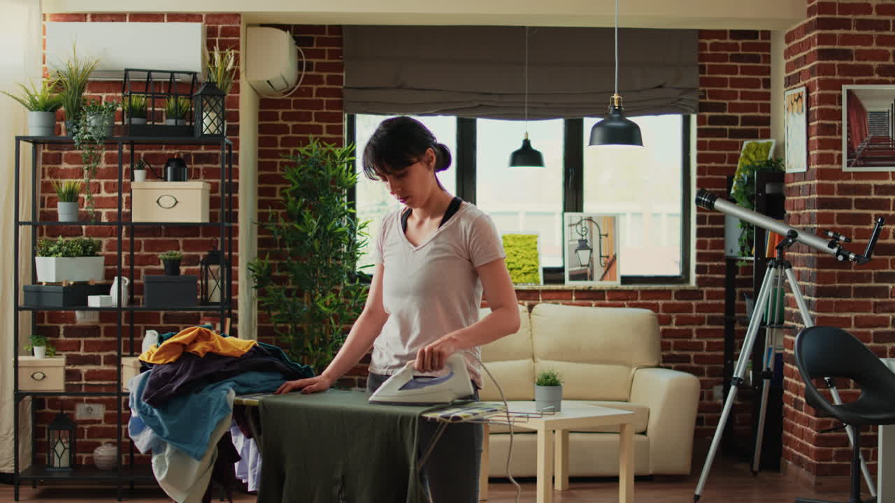 Modern woman ironing clothes at home after doing laundry