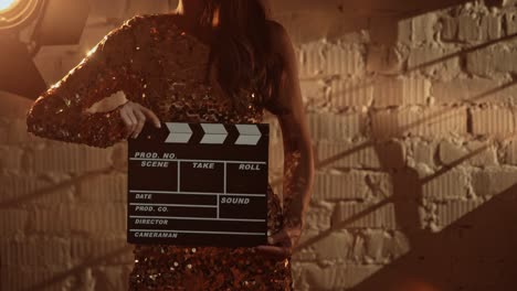 Woman in Golden Dress Holding Clapperboard on Film Set