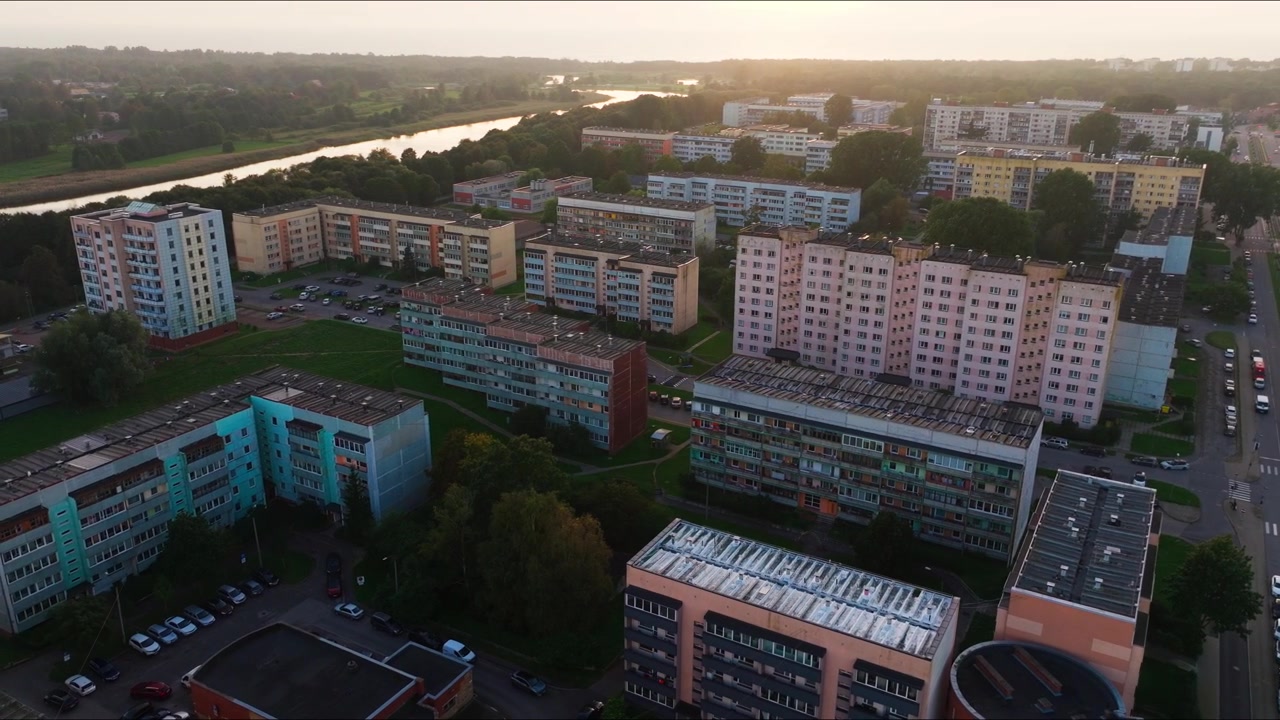 Aerial panorama of Soviet apartment district beside calm lake at sunset glow