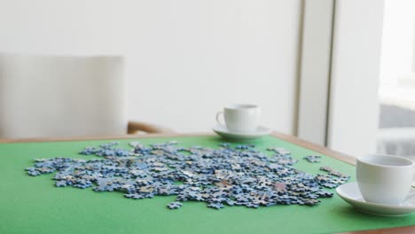 video of puzzles and cups of coffee on green table