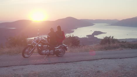 couple on motorcycle at sunset viewpoint