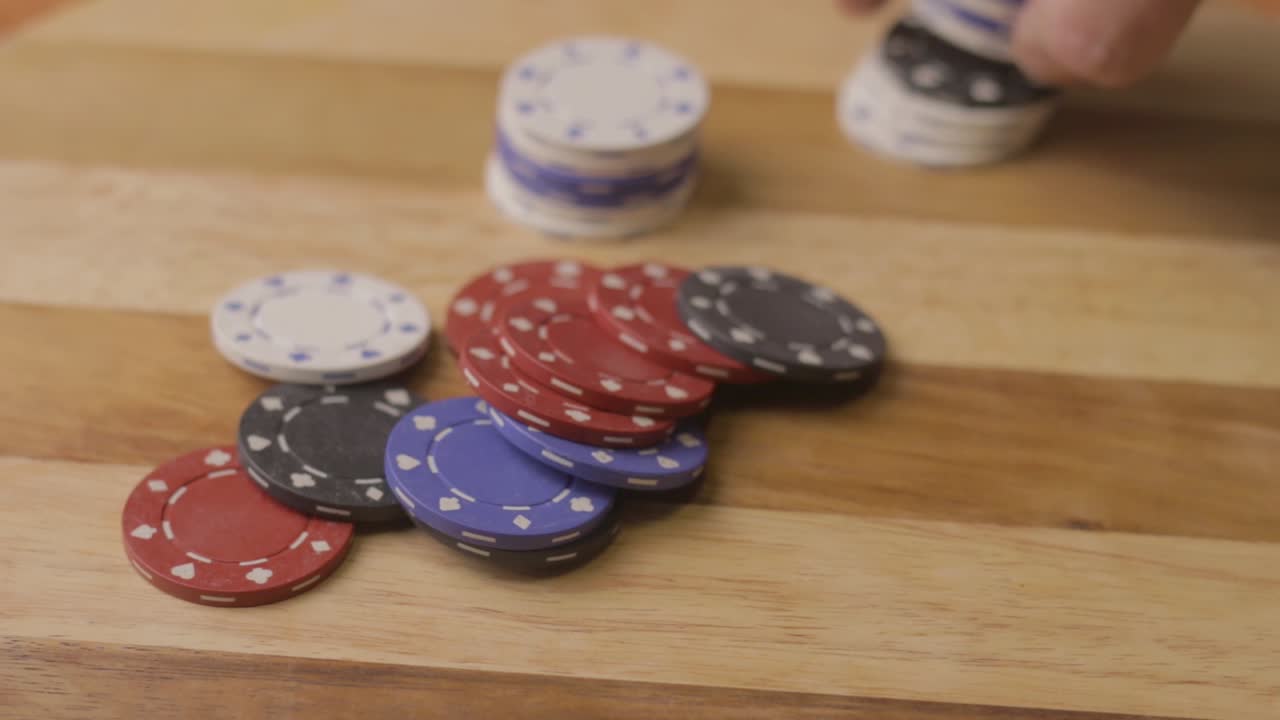 static shot of a man counting poker chips and pushing the stack