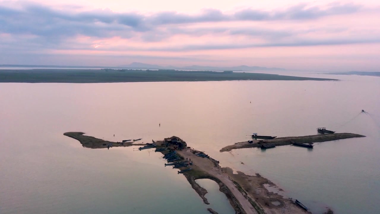 Video drone che sorvola la stretta penisola di Hel, spiagge sabbiose, barche da pesca ancorate, capanne rustiche, acque calme della baia e una tranquilla luce serale pastello sotto cieli cupi. Nessuna persona visibile