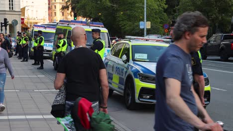 police officers guard the street during protest in stockholm, sweden, with patrol cars in background