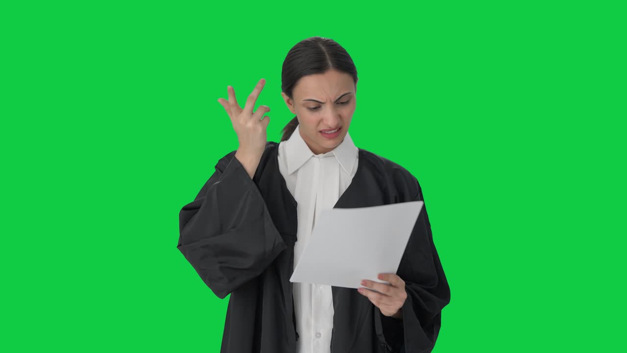 Avvocatessa indiana confusa che legge fascicoli legali su schermo verde