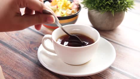 persona disfrutando de café con un postre de colores