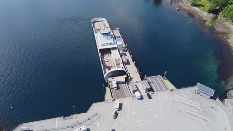 unloading ferry oppedal to road e-39 at lavik ferry pier in norway - beautiful bacwards moving aerial showing ferry before revealing harbour with ferry queue and road - norway