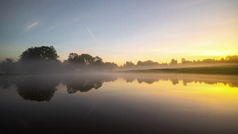 Nachtzeit,-Sonnenaufgang,-Tageszeitraffer-Mit-Nebligem-Nebel,-Der-Aus-Einem-See-Bei-Einer-Hütte-Verdunstet