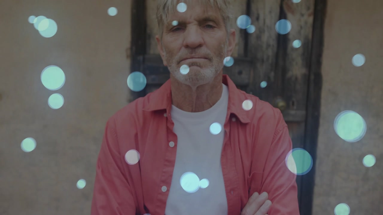 Man adjusting rolled sleeves, crossing arms by stucco wall, generating fashion bokeh overlay