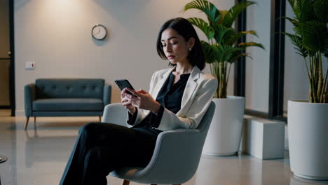 businesswoman using smartphone in a waiting room