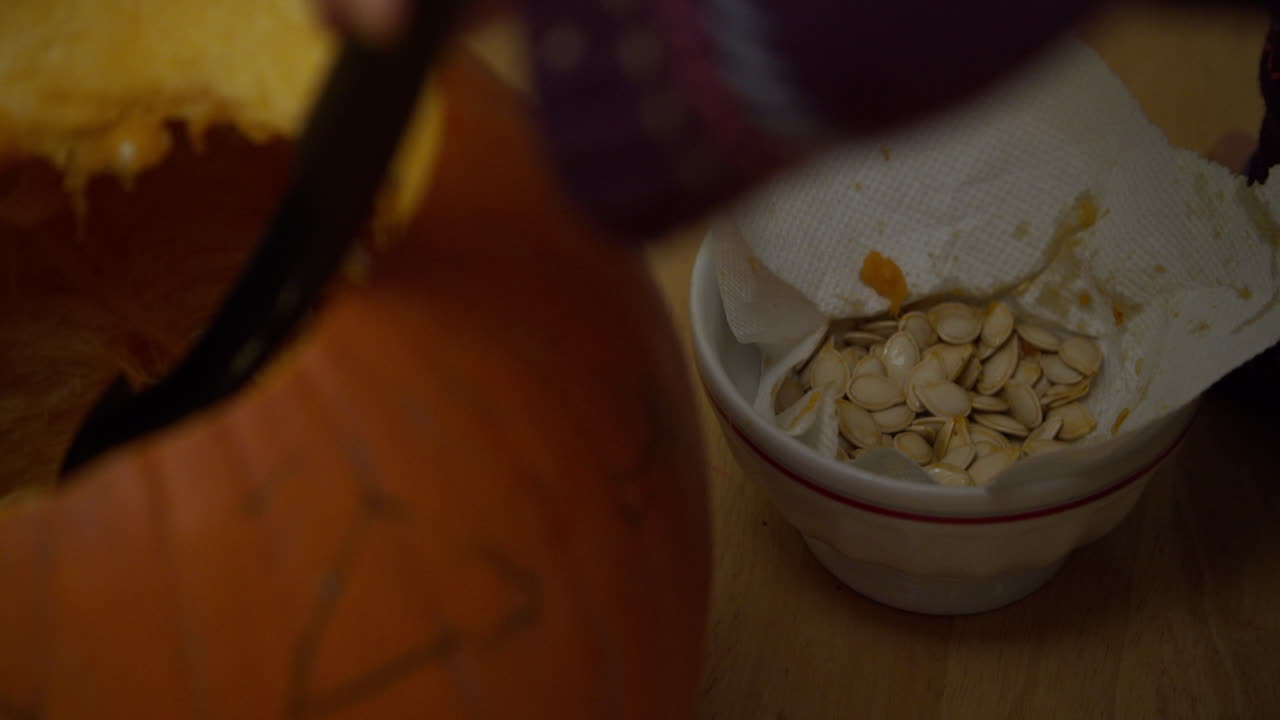 두 명의 어린 아이들이 할로윈을 위해 호박에서 씨 ⁇ 을 제거하고 있습니다.