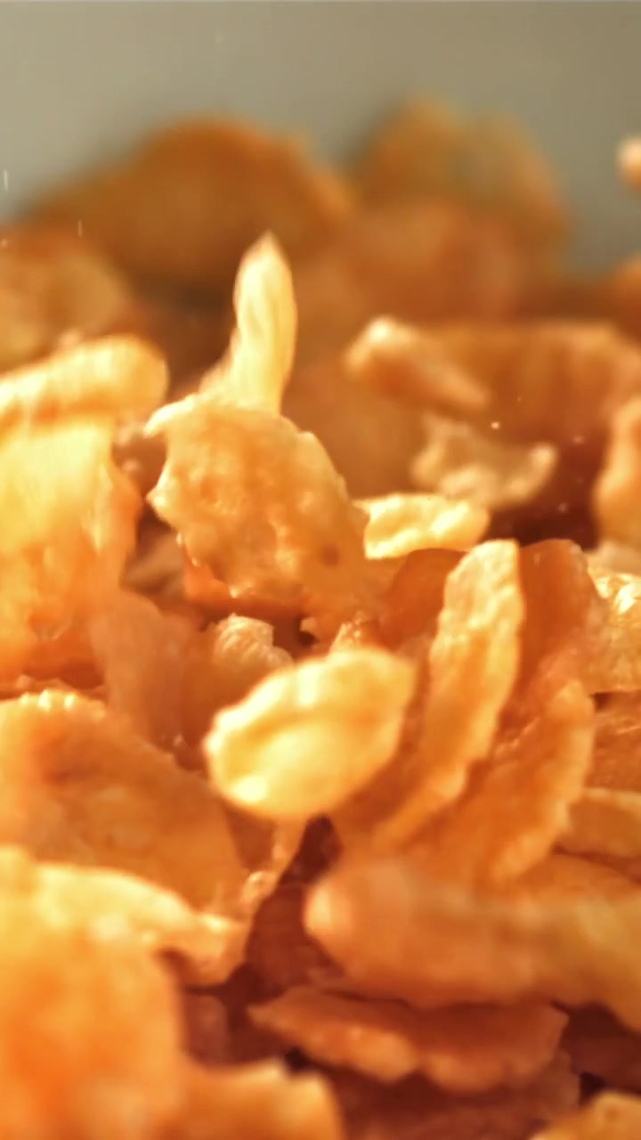 Cornflakes dorati che cadono al rallentatore in una ciotola.