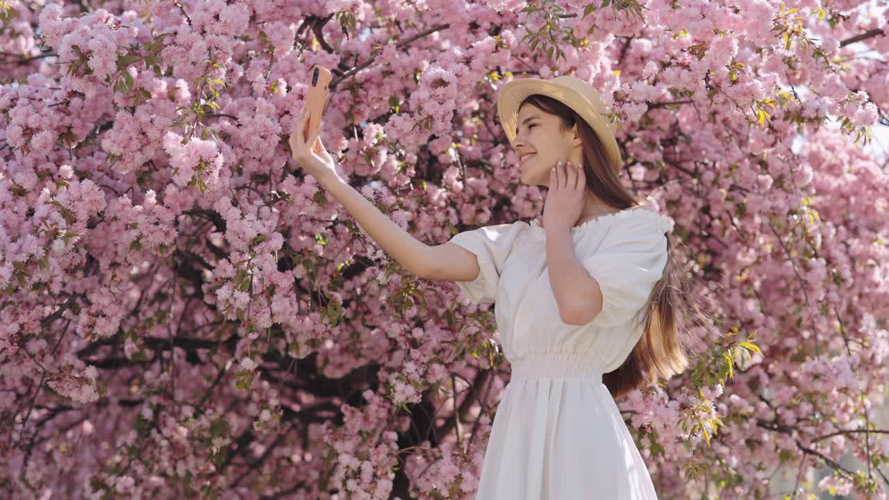 Woman taking a selfie under a cherry blossom tree