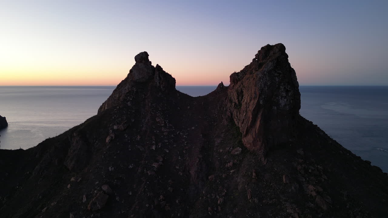 Take a mountain aerial view with two peaks and sea in the background