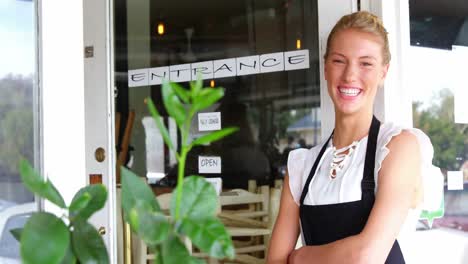 portrait of smiling waitress standing with arms crossed