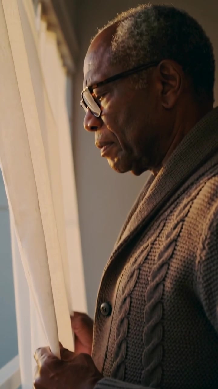 Vertical video: Touching sheer curtain man in cardigan parting window at home to see sun