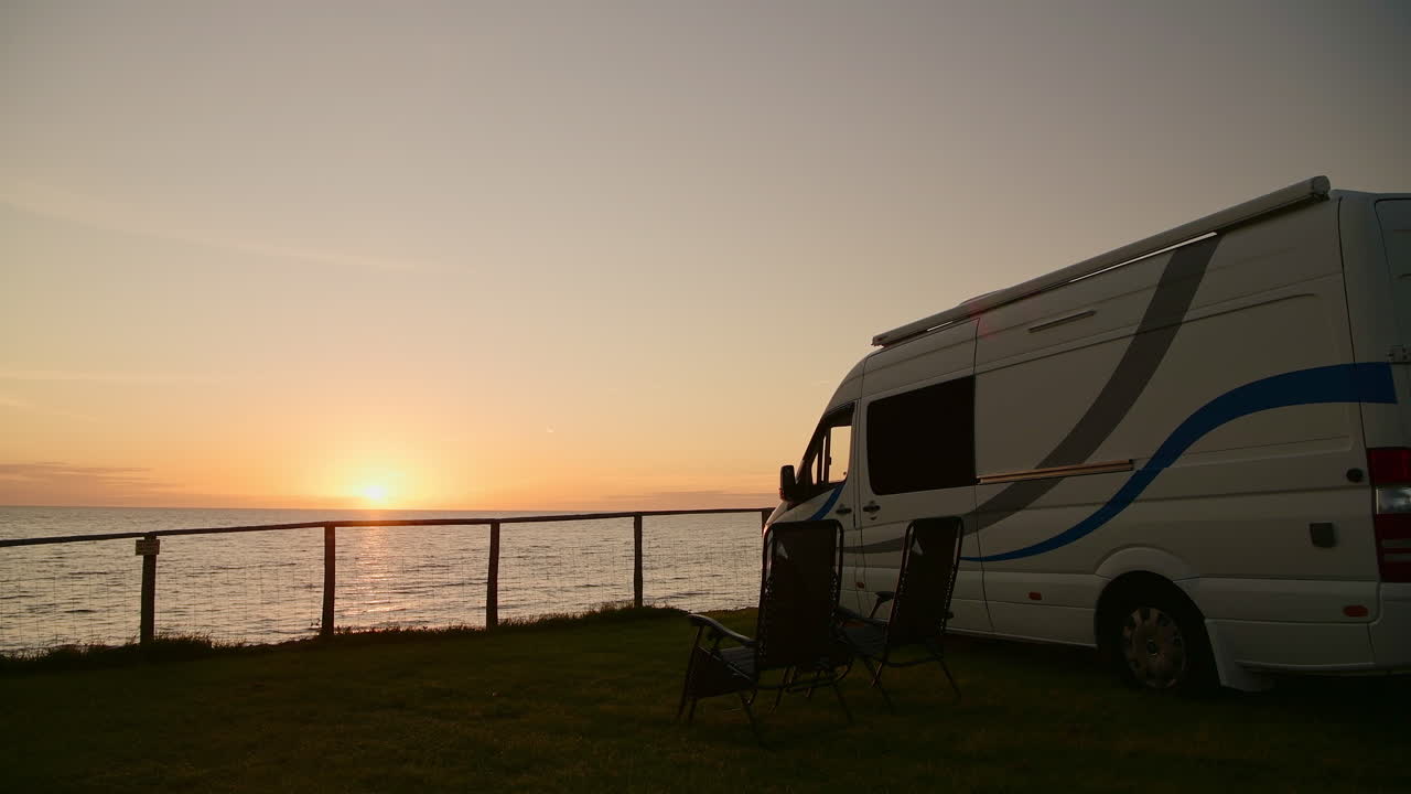 Camper van parked on coast with beautiful seafront sunset view, camping concept