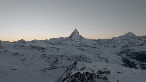 impresionante antena de drones de montaña con una vista épica de matterhorn zermatt en los alpes suizos al atardecer durante el invierno con un cielo dorado y un avión sobrevolando
