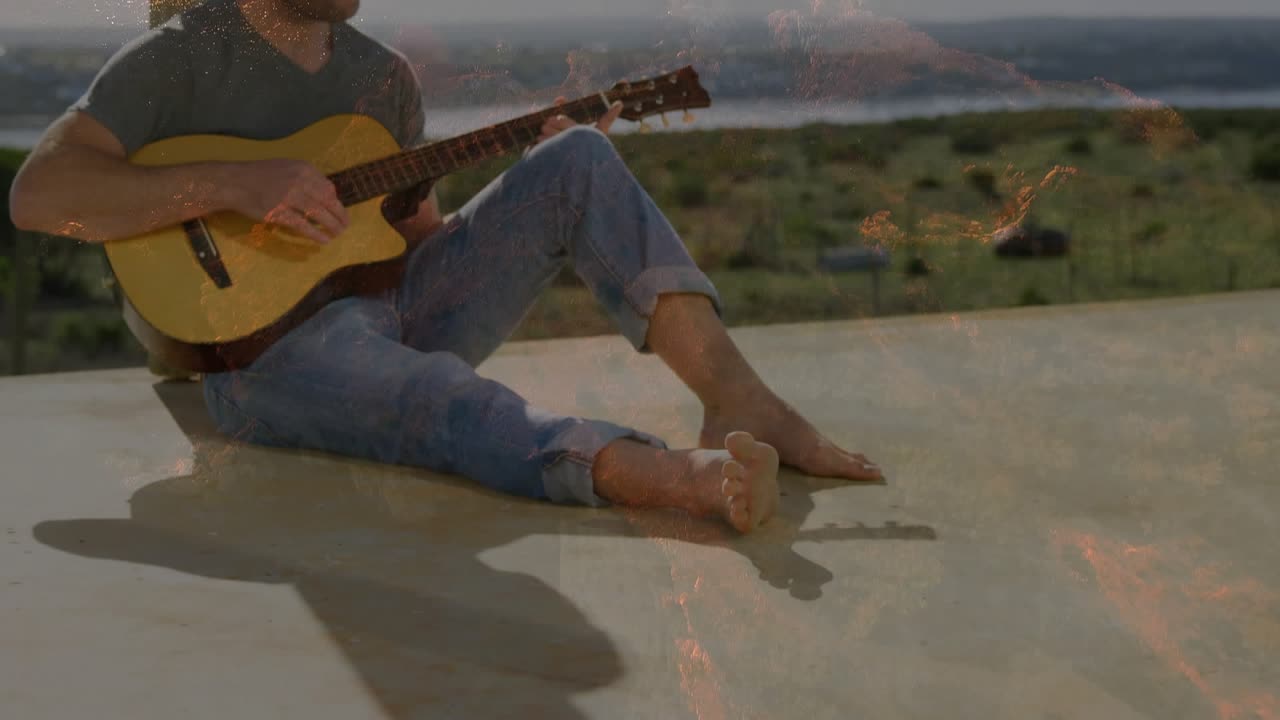Seated man starting to play wooden guitar for music on coastal patio, sun rising overlay blending