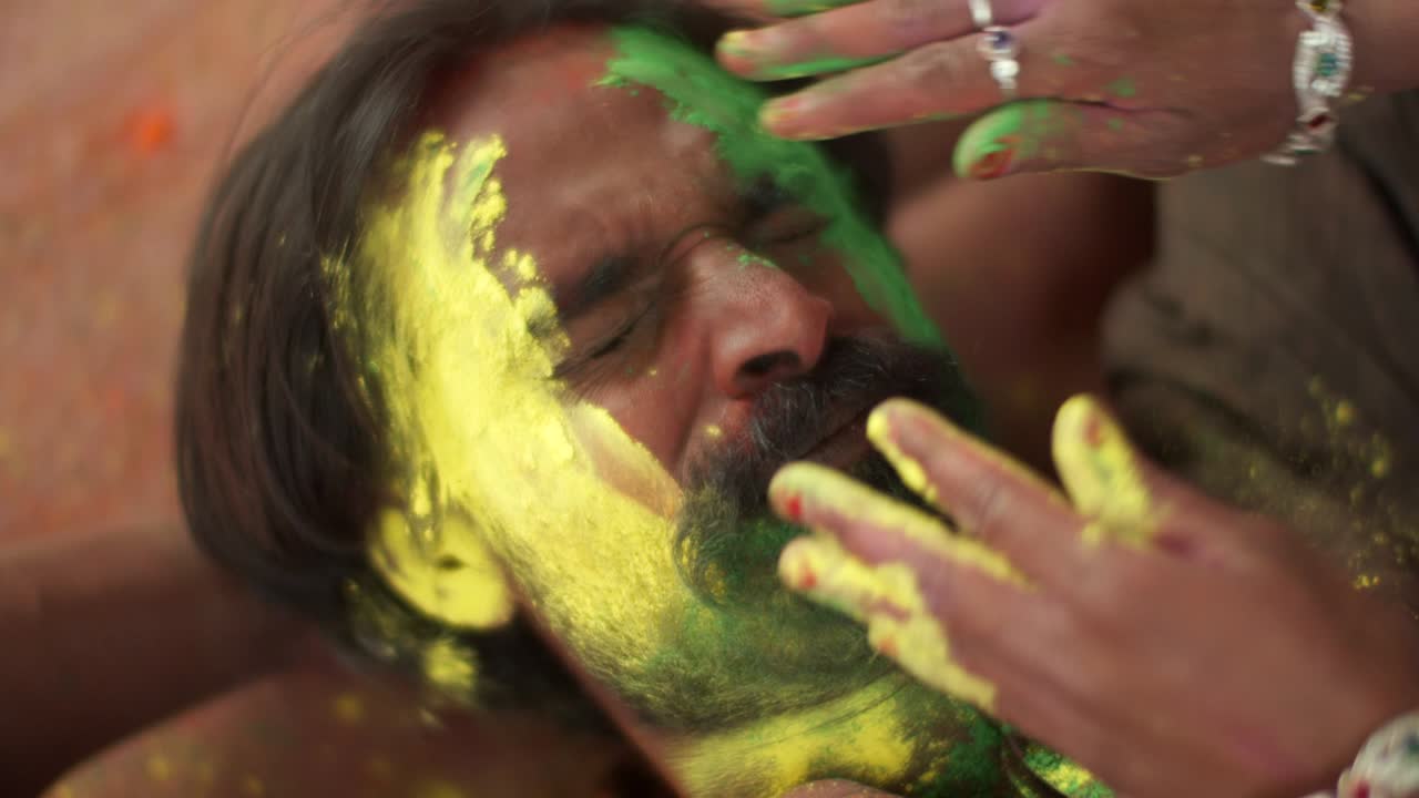 Indian man close-up of face smeared with bright Holi colors