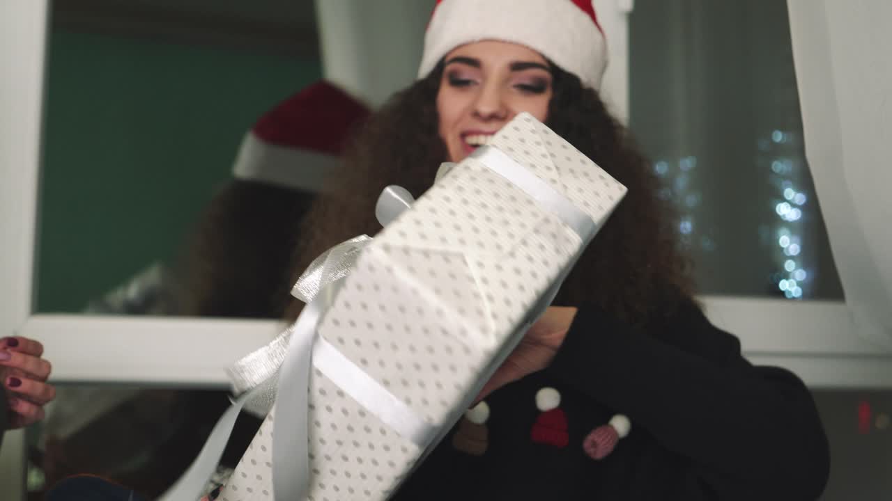 Women exchanging gifts. Smiling young women exchanging gifts on Christmas holiday at home