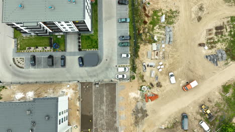 aerial view of a construction site with a partially built building, heavy machinery, and construction materials scattered around