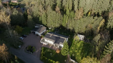 aerial view circling a sustainable house powered by solar modules, autumn evening