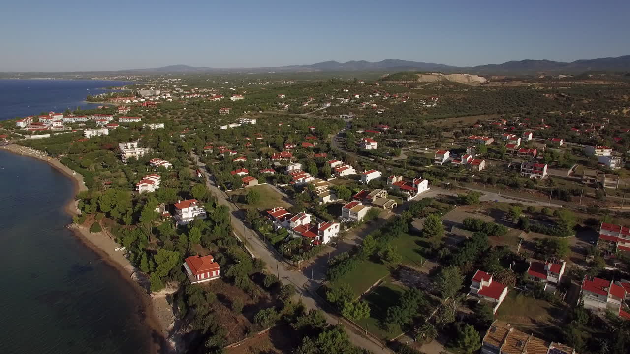 vista aérea de tierras verdes y casas en la costa del mar de la playa de trikorfo, grecia