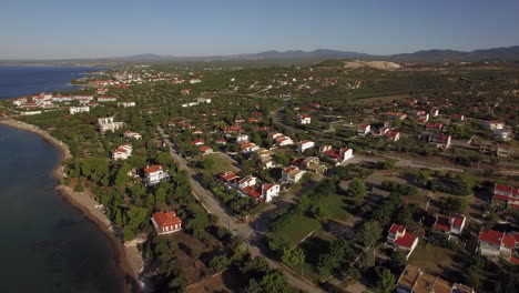 vista aérea de tierras verdes y casas en la costa del mar de la playa de trikorfo, grecia