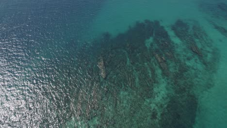 Felsenriffe-Unter-Flachem-Türkisfarbenem-Meer-Mit-Sonnenlichtreflexion-Auf-Der-Oberfläche