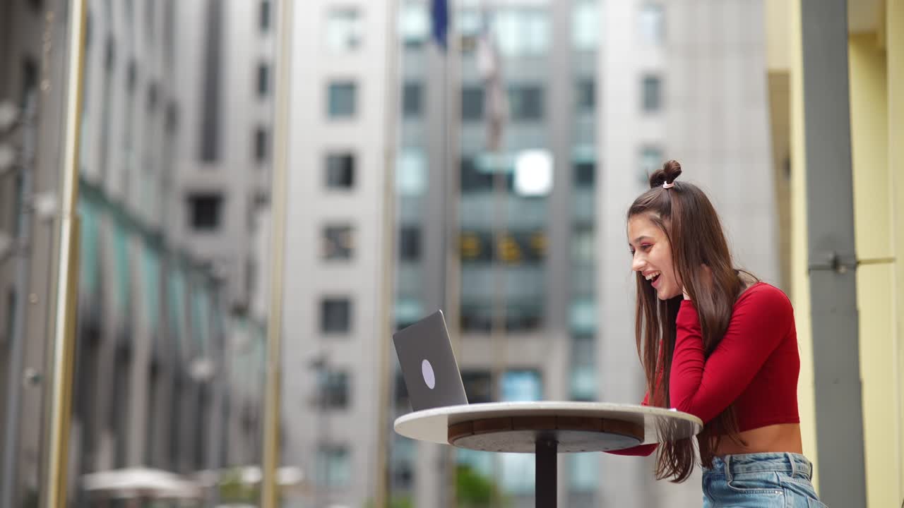 mujer joven trabajando en una computadora portátil en un café de la ciudad