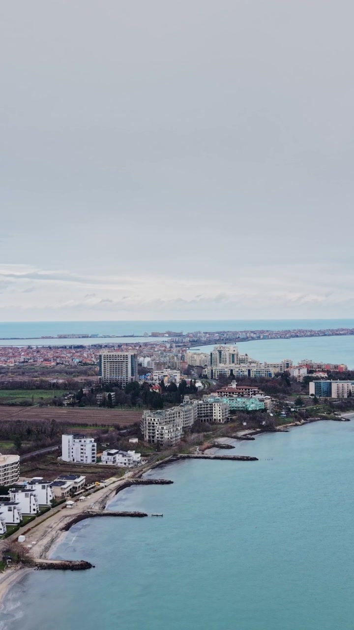 Kustlinjevy över stadsområde och hav under grå himmel