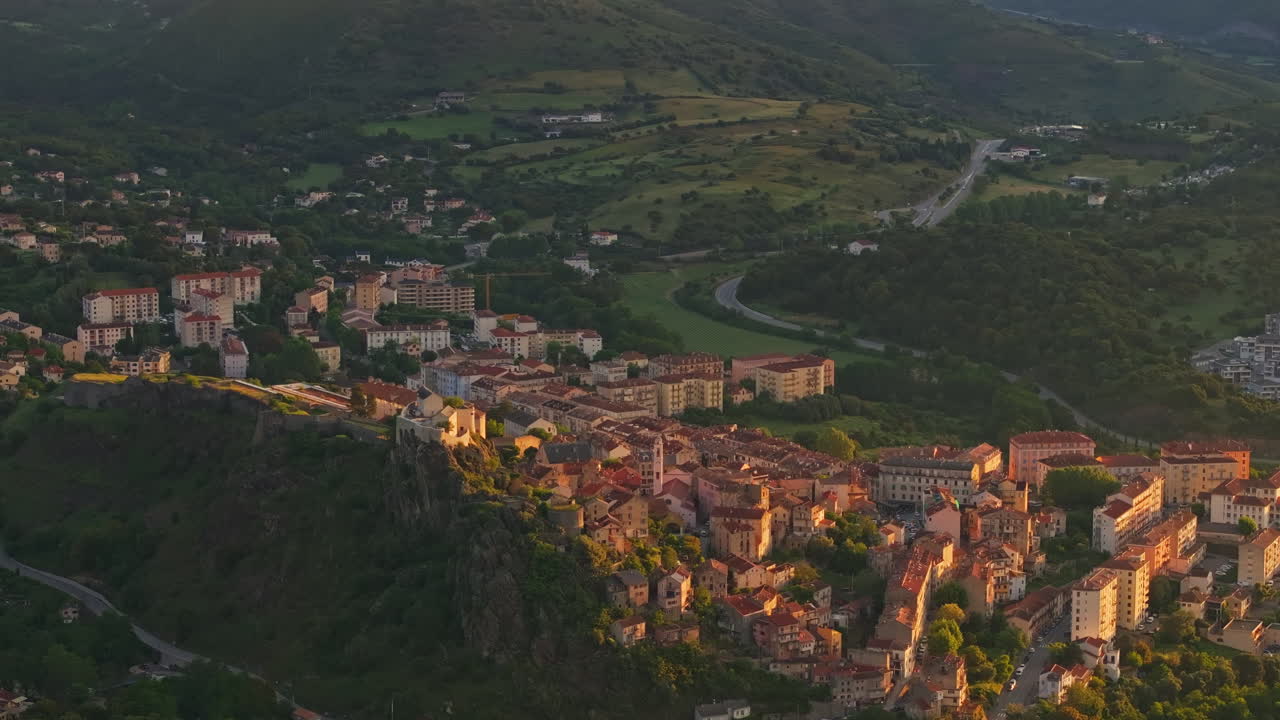 Early morning, sunrise. Aerial view of the Old town of Corte in Corsica, France. First lights, golden hour. View of the scenic mountainous landscape valley