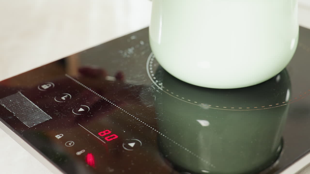 Close up of thick red soup or sauce actively bubbling inside pastel green pot on electric stove, highlighting cooking process, vibrant texture, and rich color