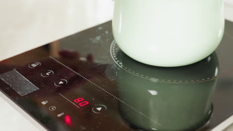 close up of thick red soup or sauce actively bubbling inside pastel green pot on electric stove, highlighting cooking process, vibrant texture, and rich color